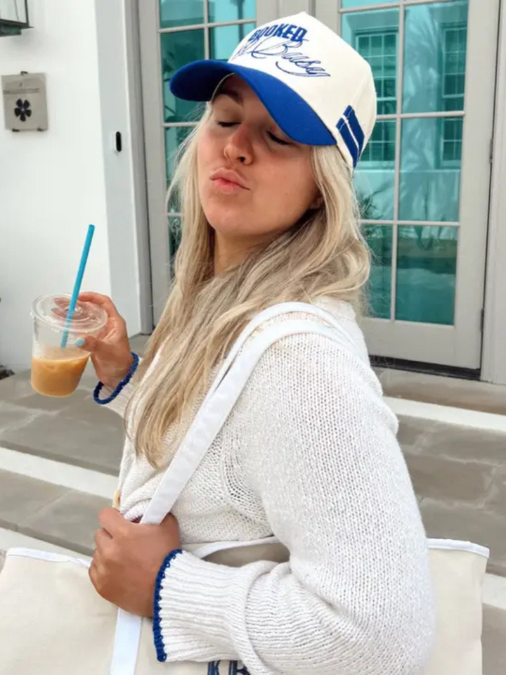Stylish woman wearing the KENZKUSTOMZ - Booked and Busy Vintage Trucker Hat, showcasing bold royal blue design.