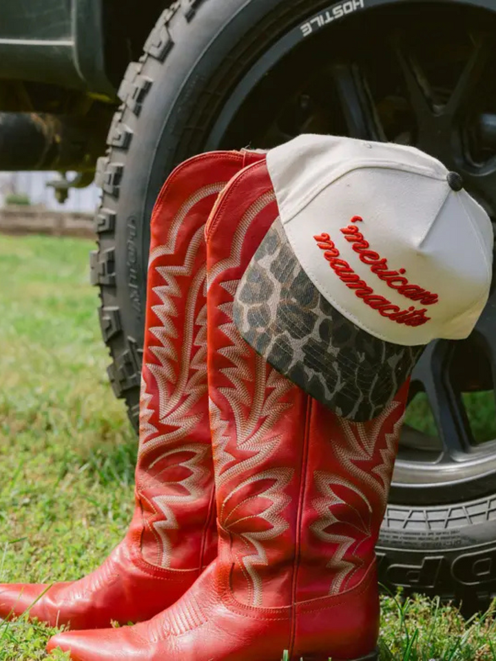 Bold KENZKUSTOMZ - 'Merican Mamacita trucker hat paired with stylish red cowboy boots, showcasing fierce Americana style.