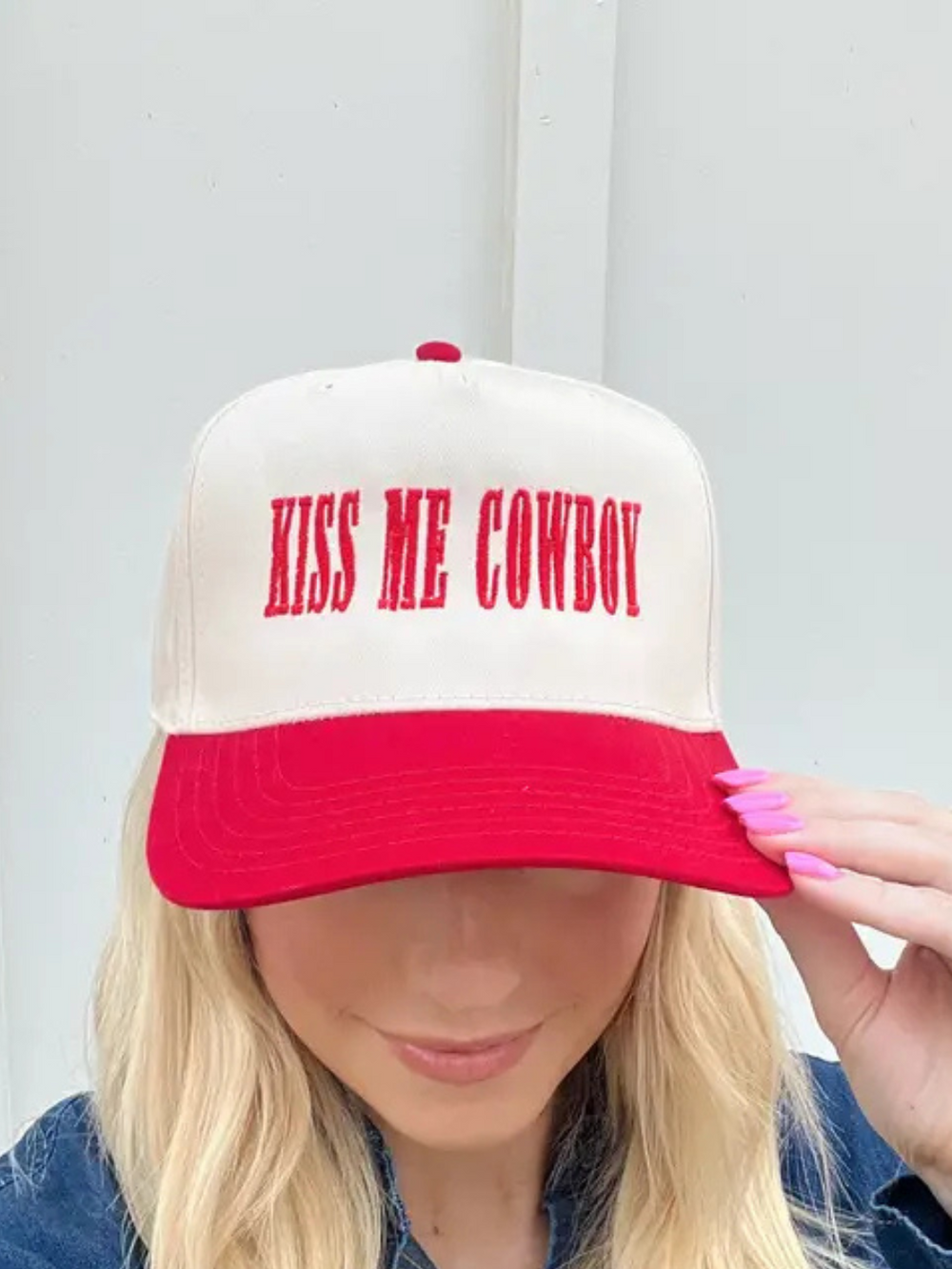 Stylish red-and-natural Kiss Me Cowboy Baseball Hat adds sass to any outfit with flirty embroidery and structured design.