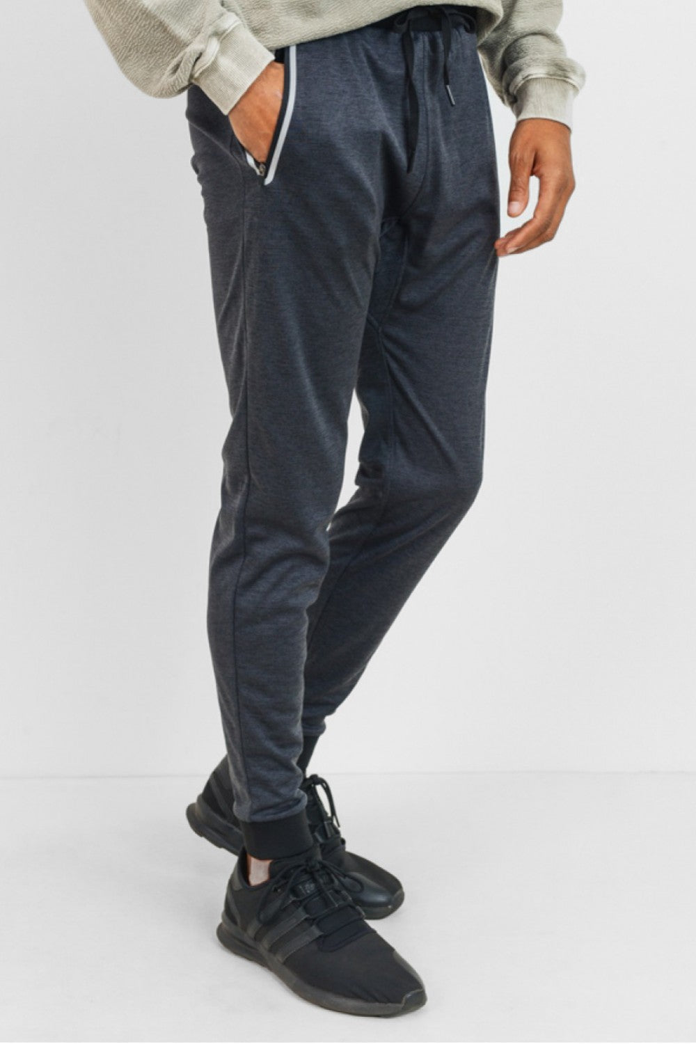 Crafted using 100% polyester melange fabric, these active joggers have two slanted and zippered pockets on each side (with contrasting frame), black ankle cuffs, and black waist band with outer drawstring cord.