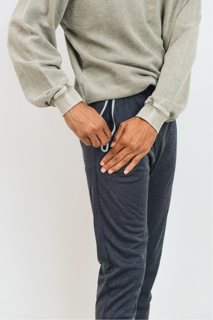 Crafted using 100% polyester melange fabric, these active joggers have two slanted and zippered pockets on each side (with contrasting frame), black ankle cuffs, and black waist band with outer drawstring cord.