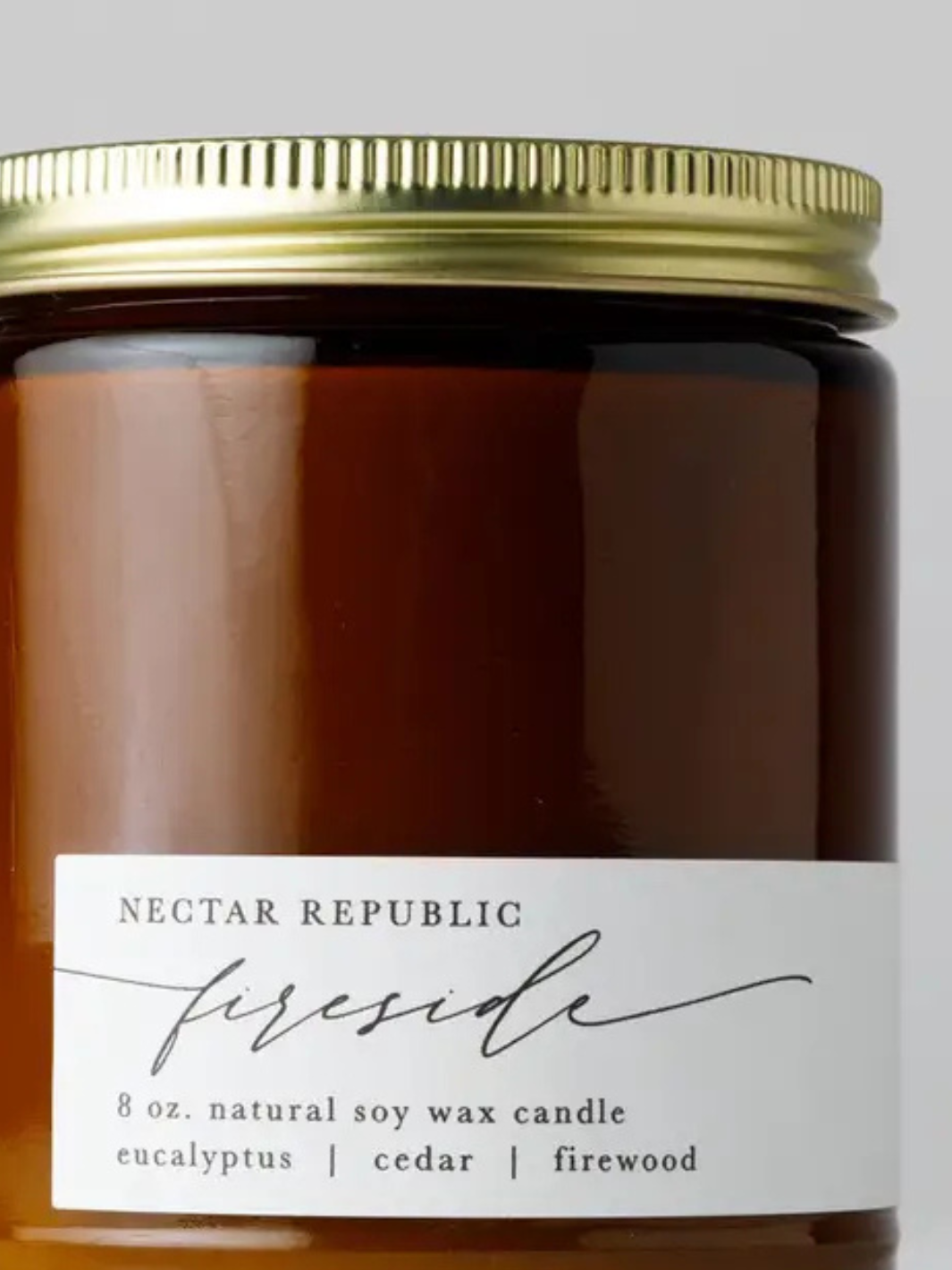 Nectar Republic Fireside 8 oz jar soy candle in amber glass with gold lid; eucalyptus, cedar, firewood.