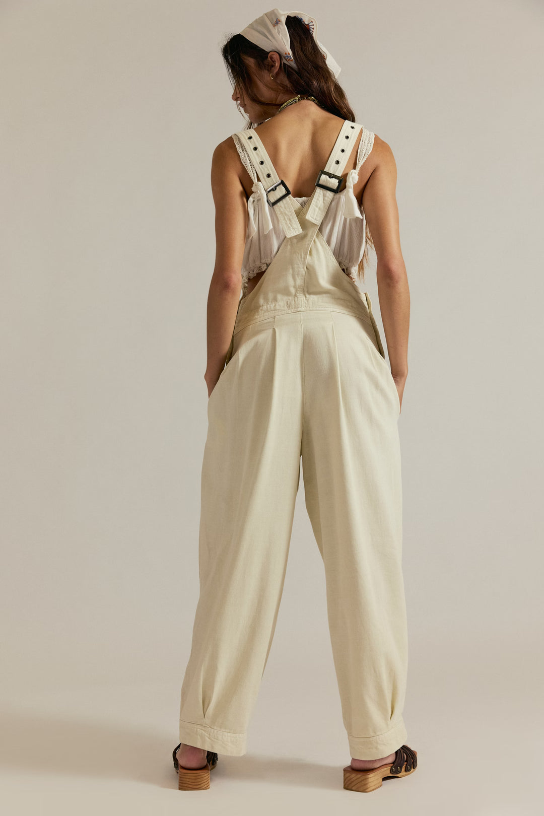 Back view of cream Felix Tapered Overalls with cross-back straps, metal buckles, and wide legs.