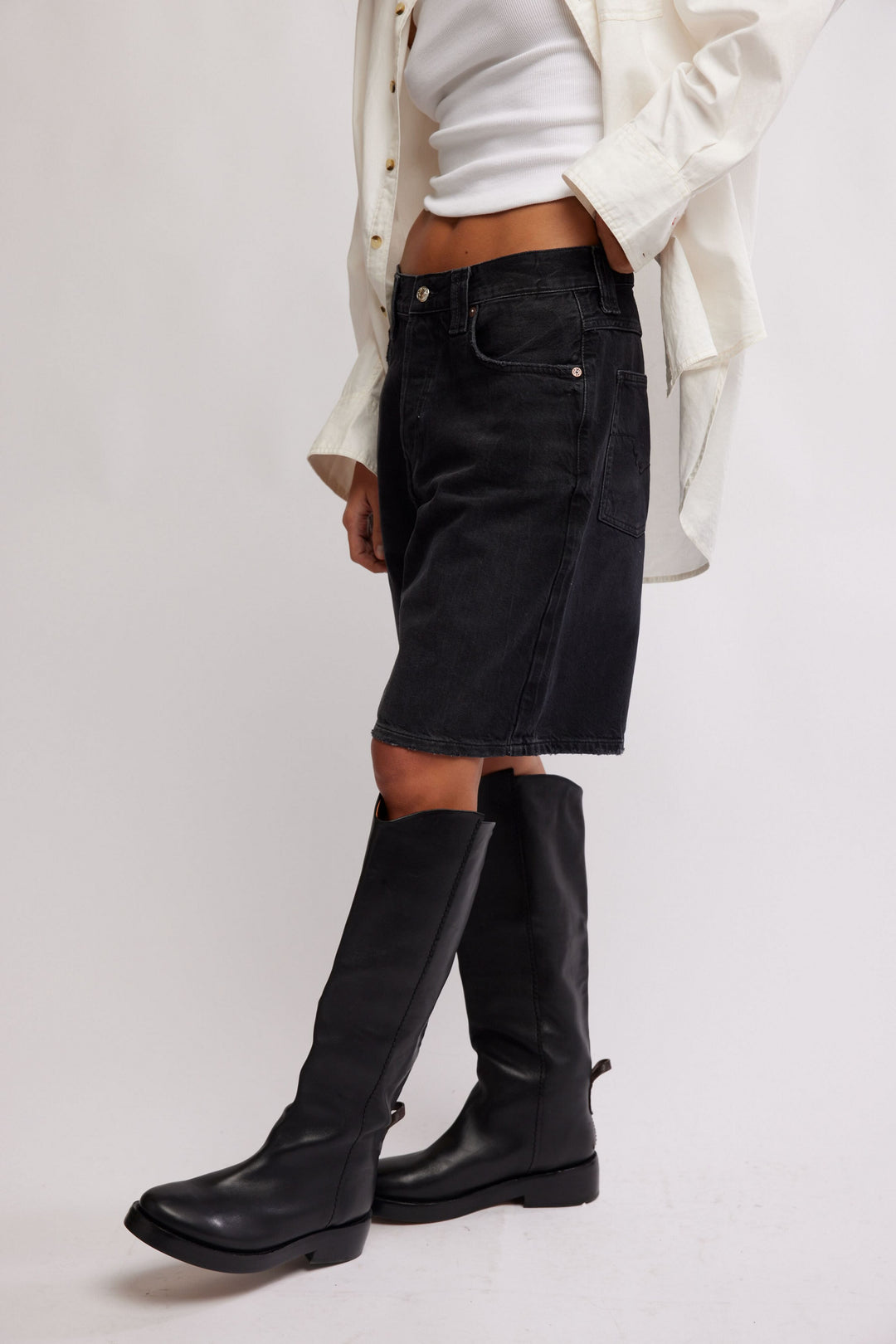 FREE PEOPLE The Montana Short in black denim, mid-rise relaxed Bermuda length, with white top and knee-high boots.