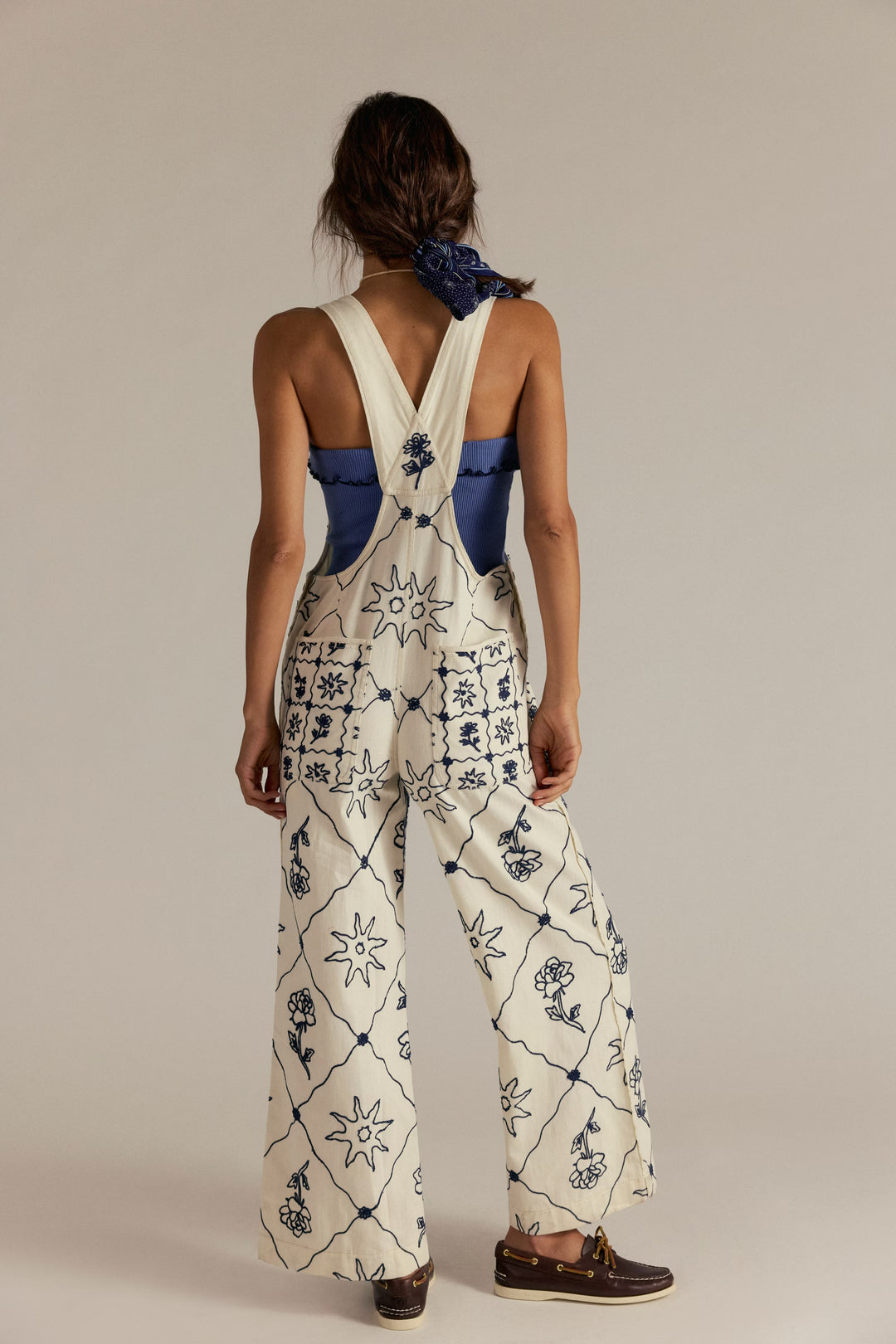 Rising Sun Overall in cream with navy embroidered suns and florals, cross-back straps, blue top underneath