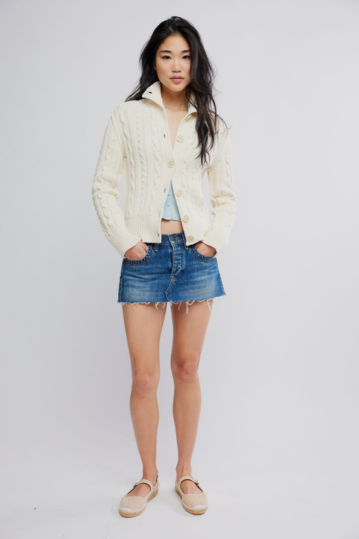 Model in cream FREE PEOPLE WTF Cable Collar Cardi with chunky cables and a collared front, denim mini skirt.