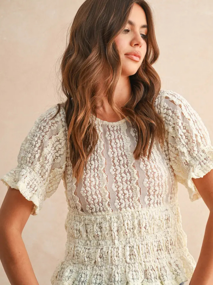 Romantic white lace blouse with puff sleeves and smocked waist on a model.