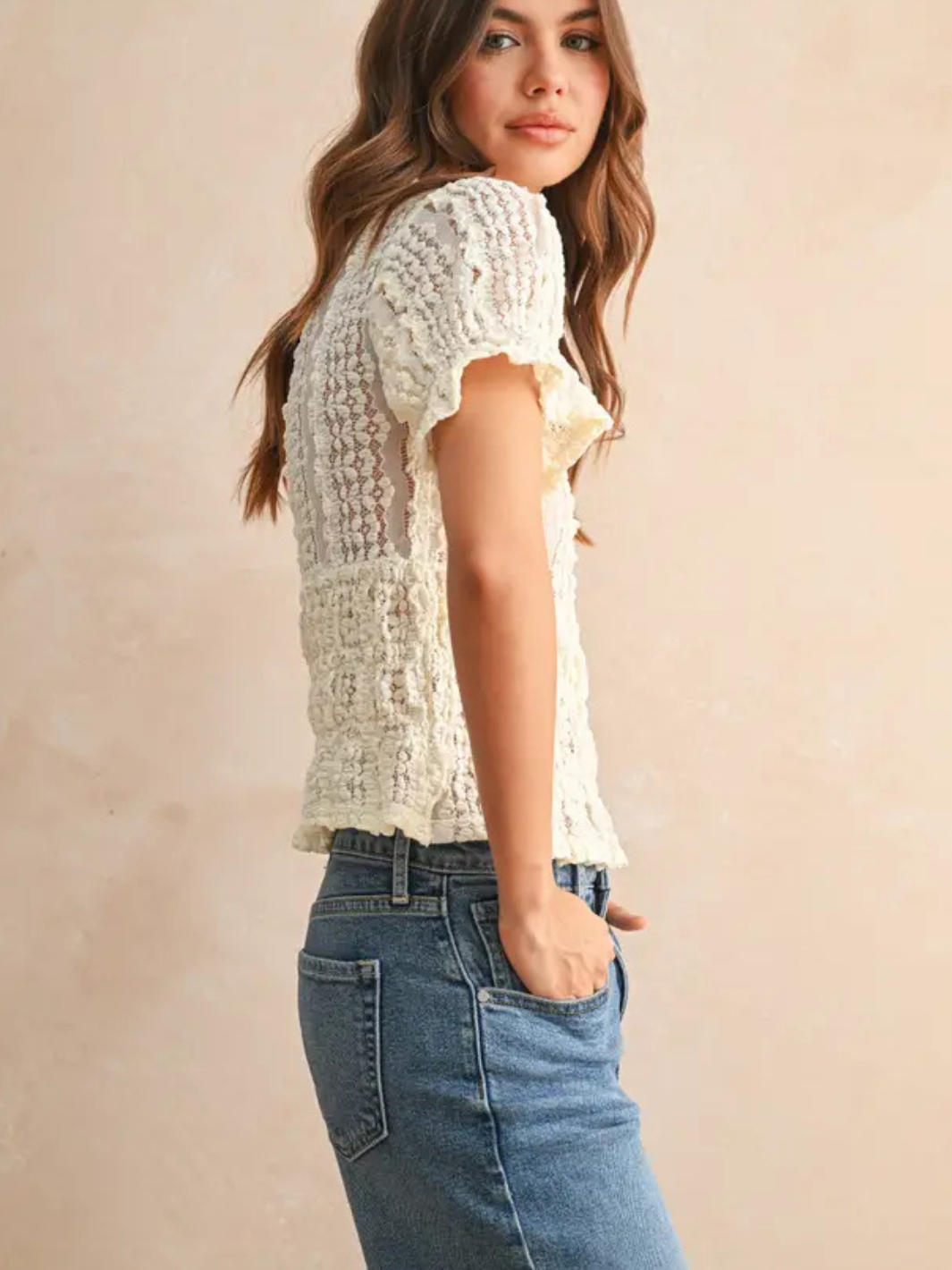 Cream ivory lace short-sleeve blouse with delicate pattern, styled with blue denim jeans.