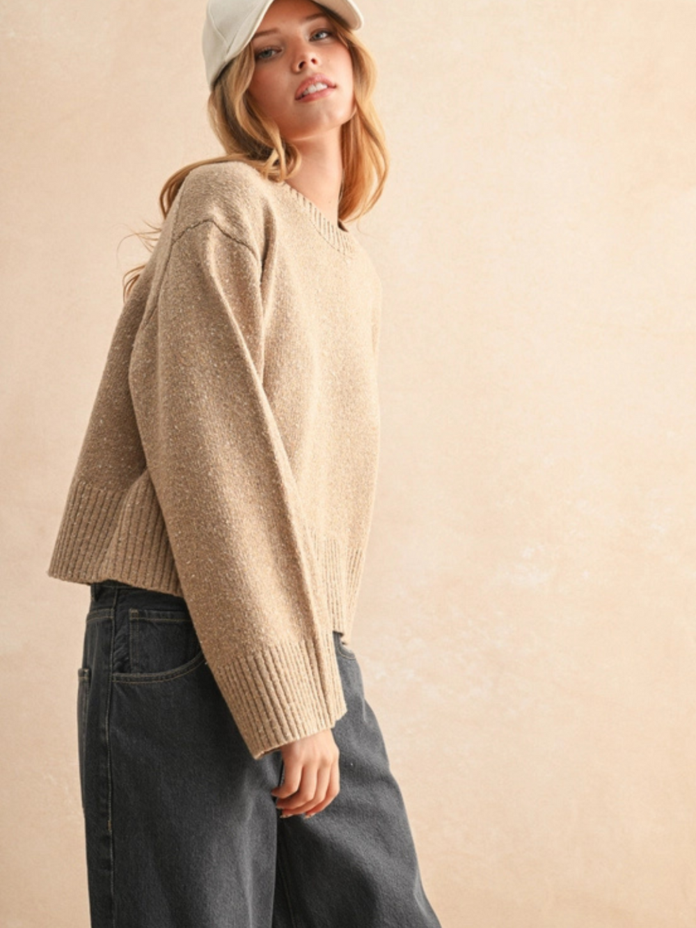 Beige sprinkled-effect sweater with a relaxed boxy fit, styled with dark jeans.