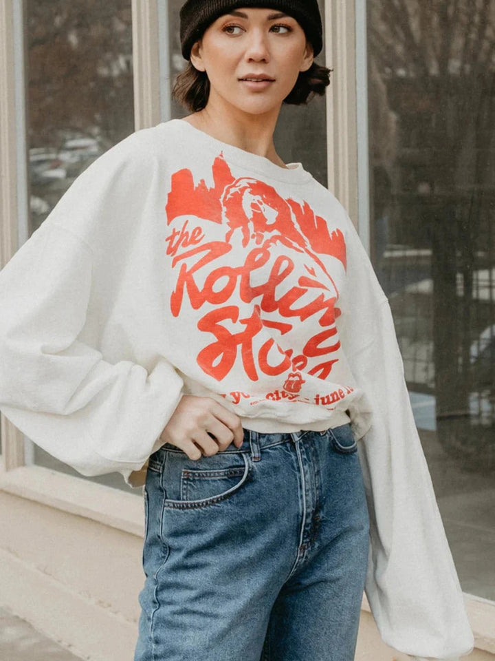 A woman in a white Rolling Stones sweatshirt and jeans looking relaxed and stylish. People of Leisure