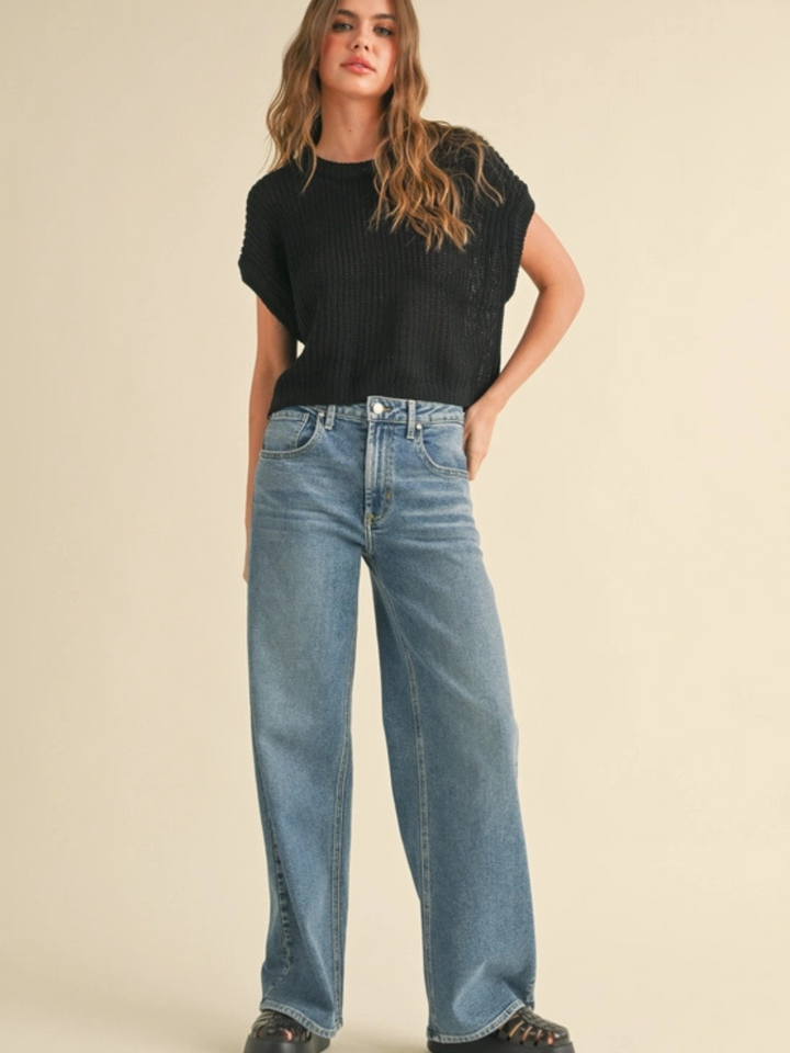 The Capsule Knit Sleeveless Sweater Top in black, relaxed knit with a boxy fit, paired with wide-leg jeans.