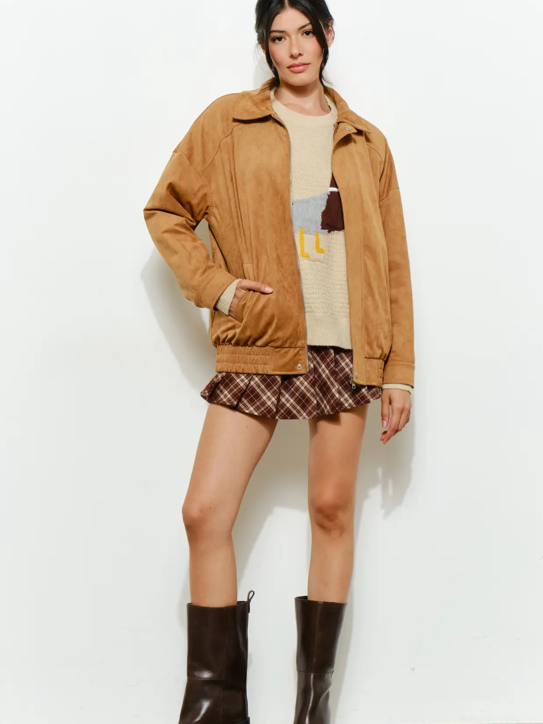 Model wearing The Halow Vegan Oversized Suede Jacket in camel, with knit sweater, plaid mini skirt, and brown boots.