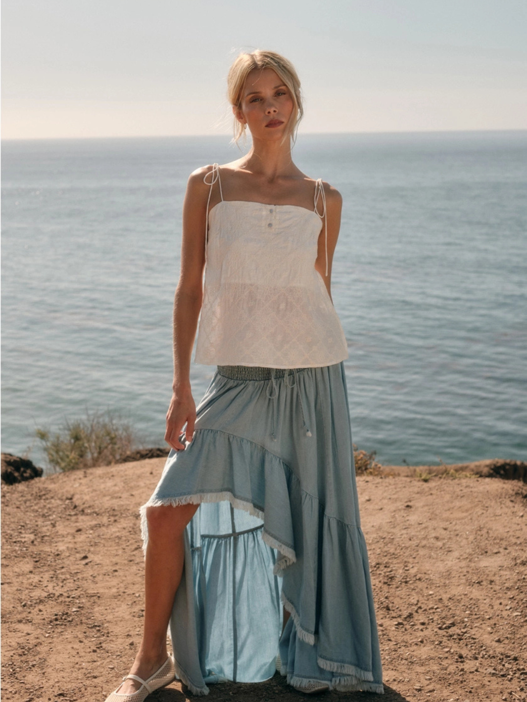 Model wearing The Seafoam Embroidered Cami with delicate floral embroidery and a straight neckline by the sea.