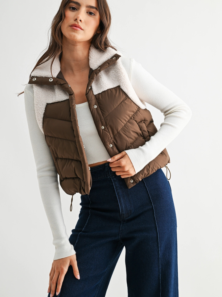 Brown The Willow Sherpa Puffer Vest with plush sherpa collar and quilted insulation, worn over a white sweater.