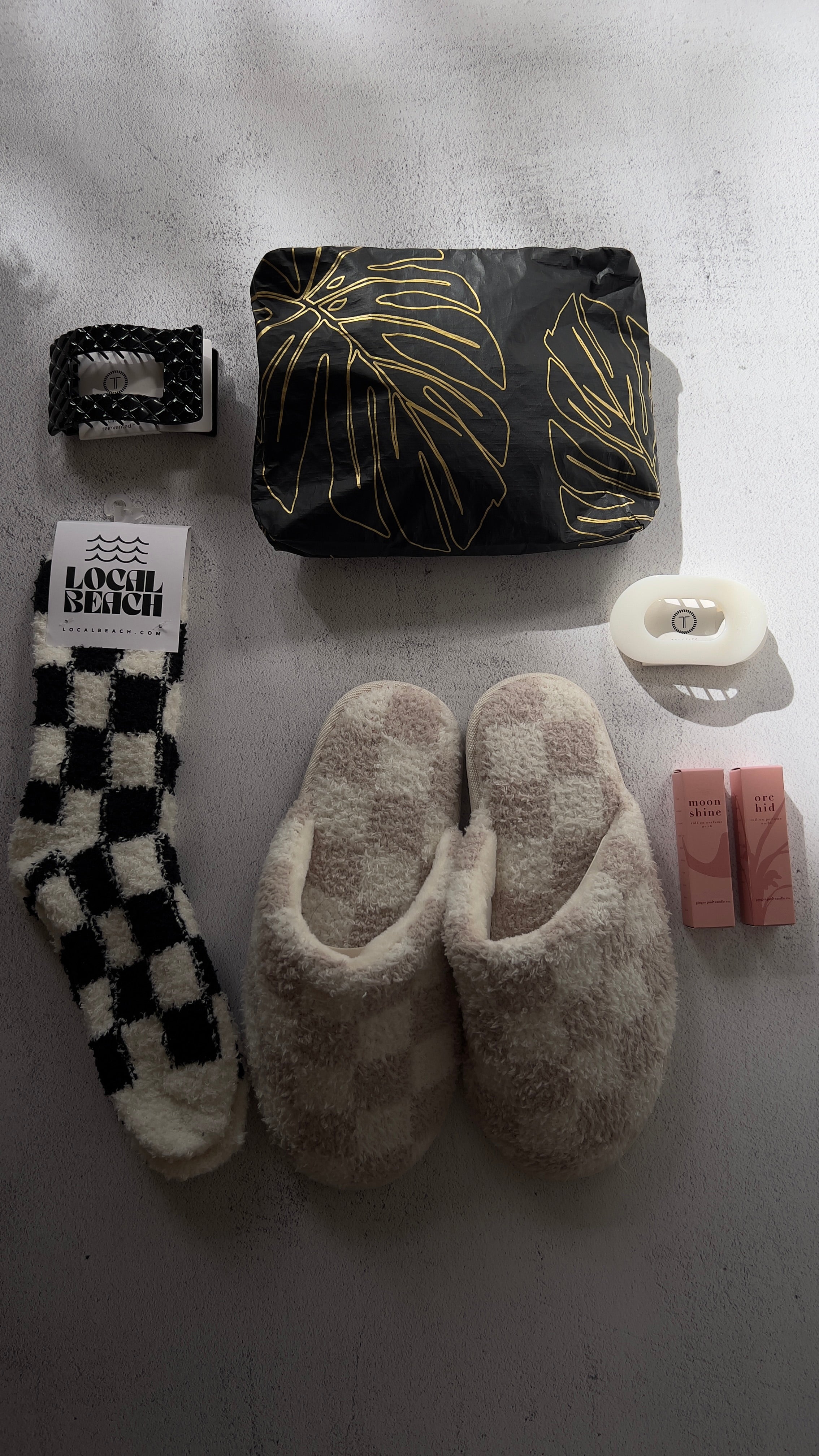 Collection of items including slippers, socks, and a pouch on a gray surface