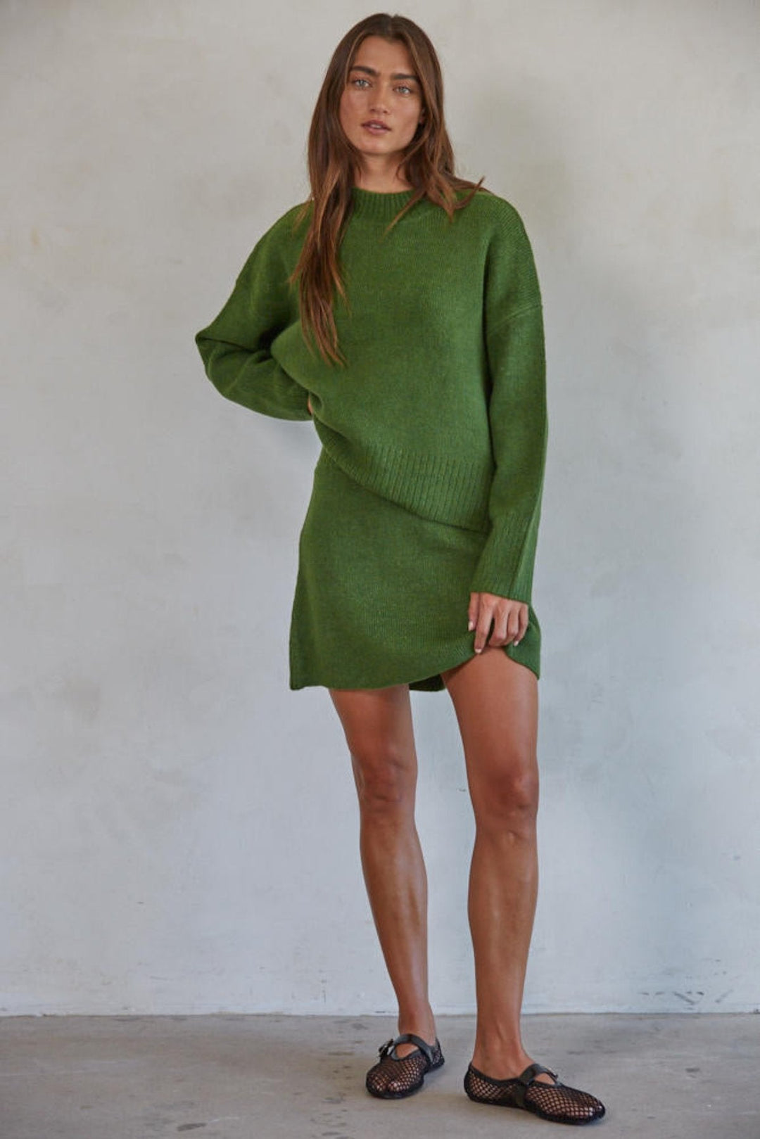 Person standing in sweater and skirt combo