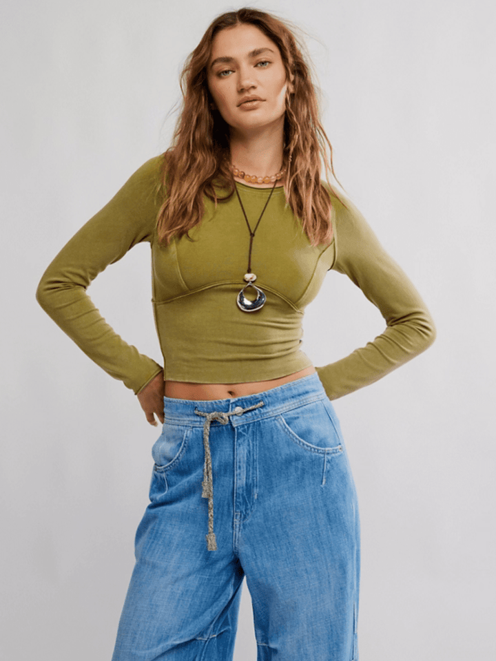 Olive-green The Protagonist Long Sleeve Top on a model, cropped fit with curved seams, paired with light denim jeans.