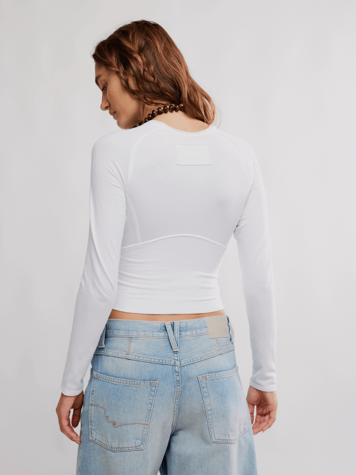 Back view of FREE PEOPLE The Protagonist Long Sleeve top in white on a model.