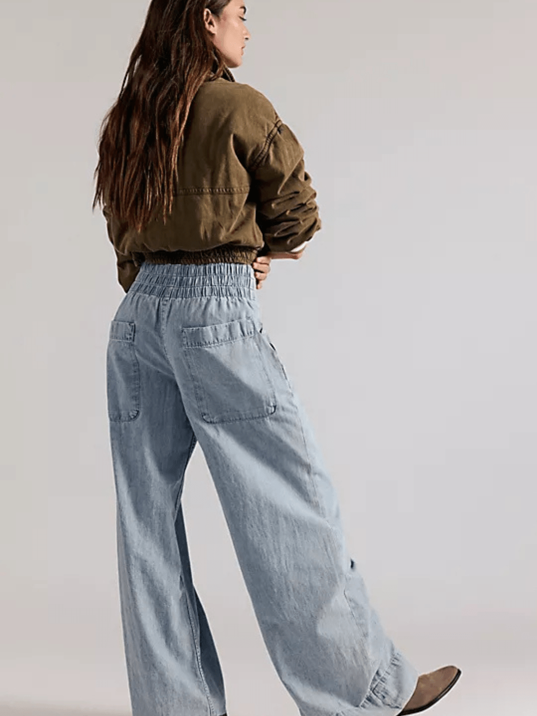 Model wearing We The Free Breezy Denim pull-on jeans, light-wash with smocked waistband and back pockets.