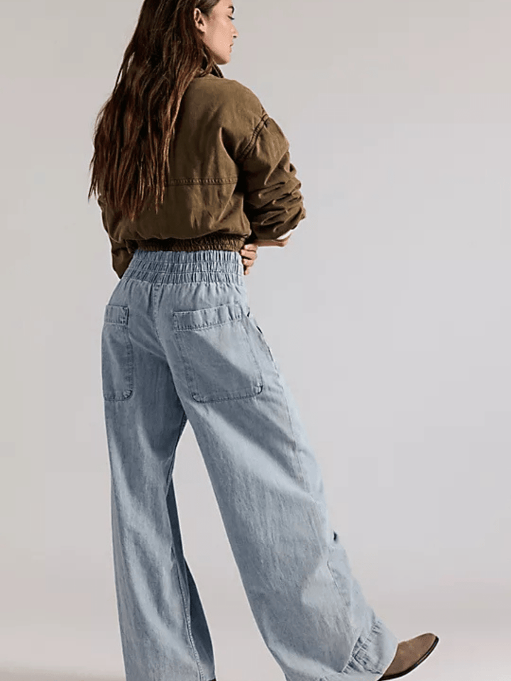 Model wearing We The Free Breezy Denim pull-on jeans, light-wash with smocked waistband and back pockets.