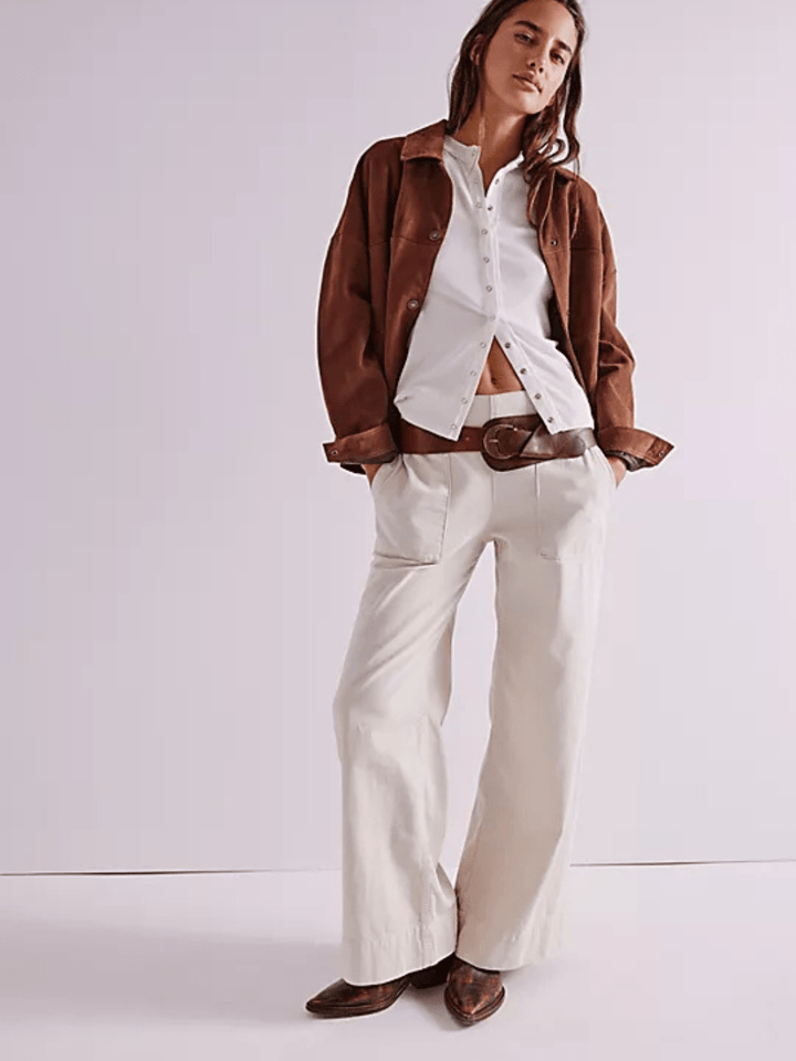 Model wearing Free People We The Free Breezy Denim Pull-On Jeans with white button-down, brown belt and jacket
