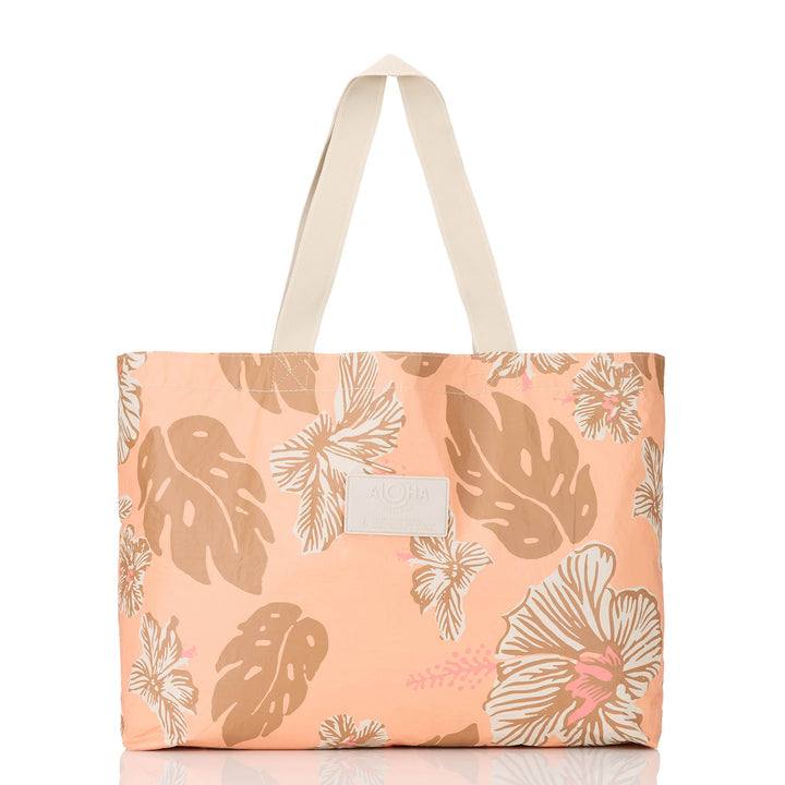 Peach Papeete Holo Holo tote with toffee-brown monstera leaves and white hibiscus and cream straps, front view