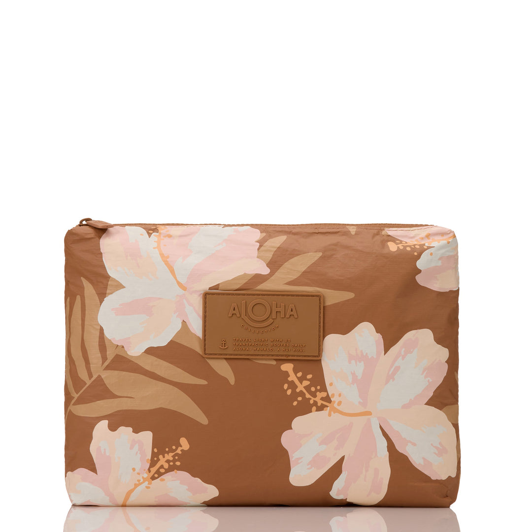 Toffee-brown Adrift Mid Pouch with large cream and blush hibiscus blooms and palm fronds, front view with the ALOHA patch
