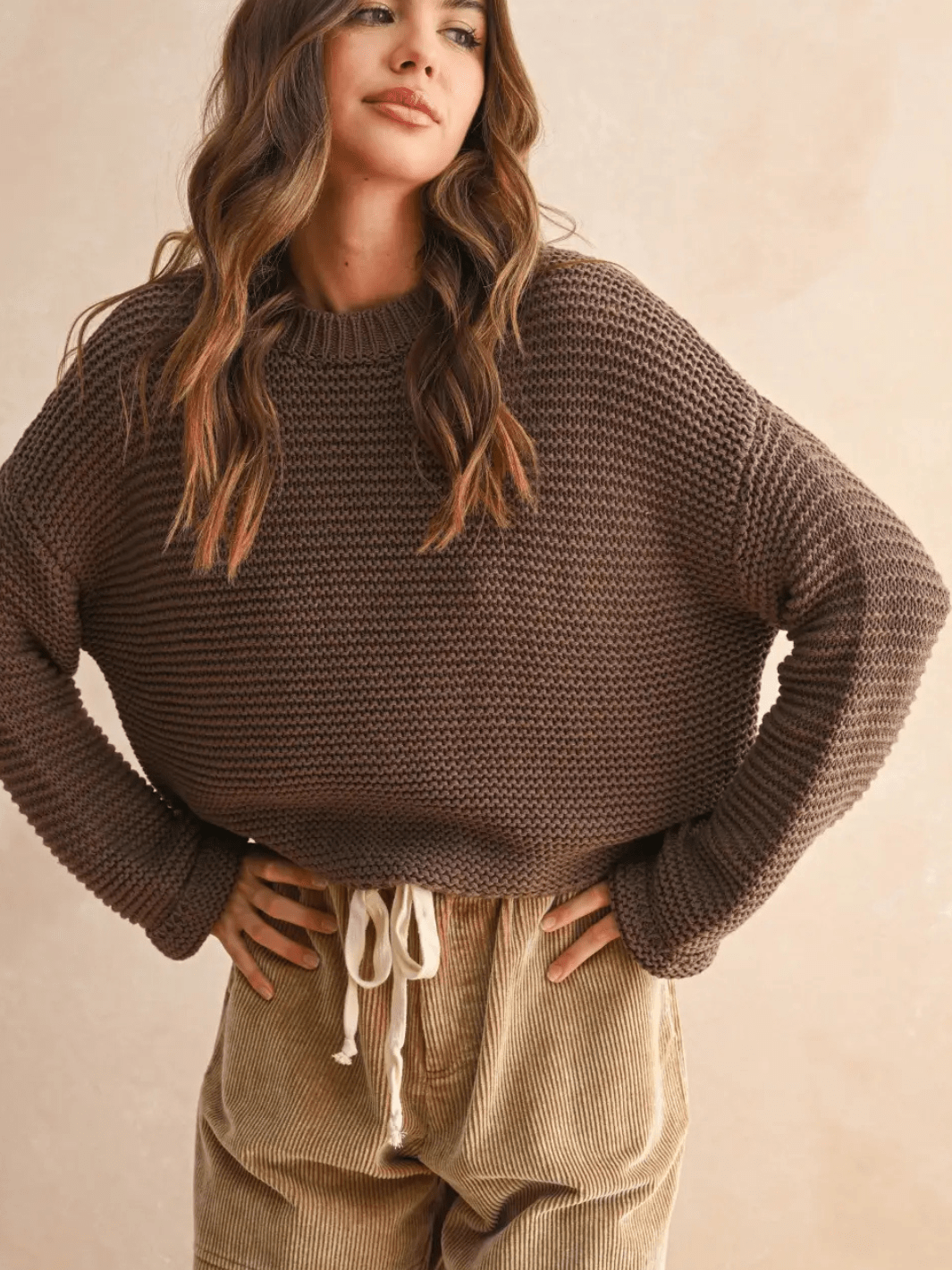 Laid-Back Luxe Chunky Knit Top in brown with relaxed oversized fit and round neckline, shown with beige corduroy pants.