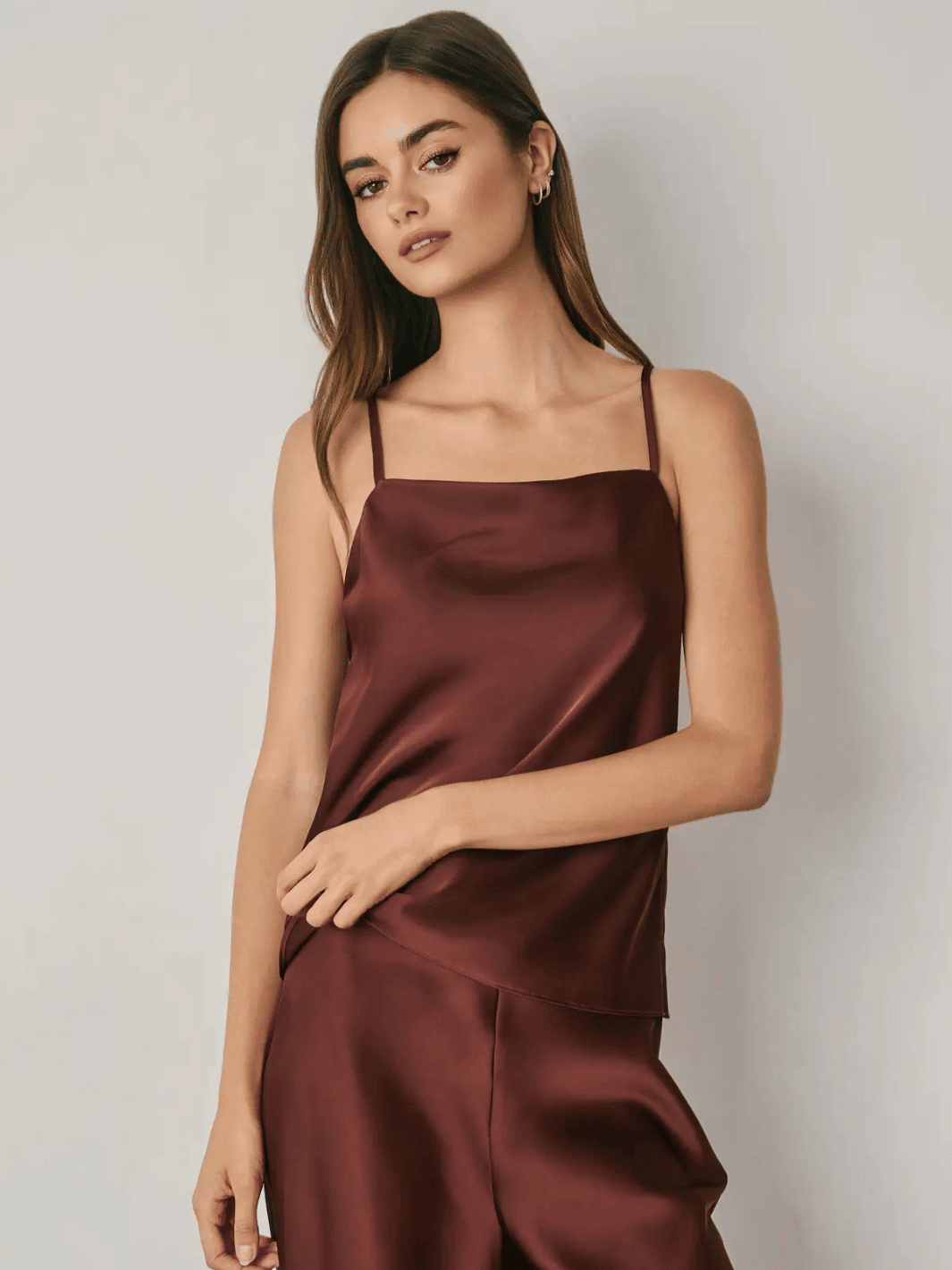 Woman wearing burgundy satin cami top with square neckline and adjustable straps