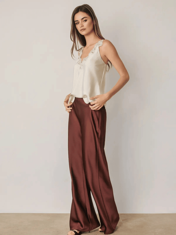 Women wearing burgundy high-rise satin straight leg pants paired with a white lace camisole top.