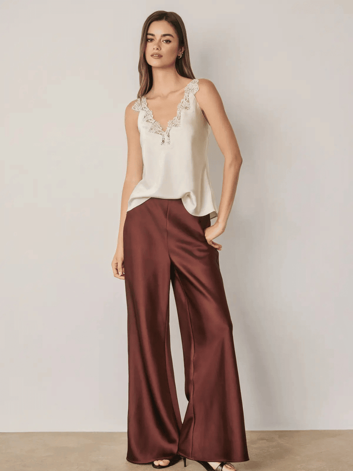 Model wearing maroon satin straight leg pants with a high-rise fit and relaxed legs.