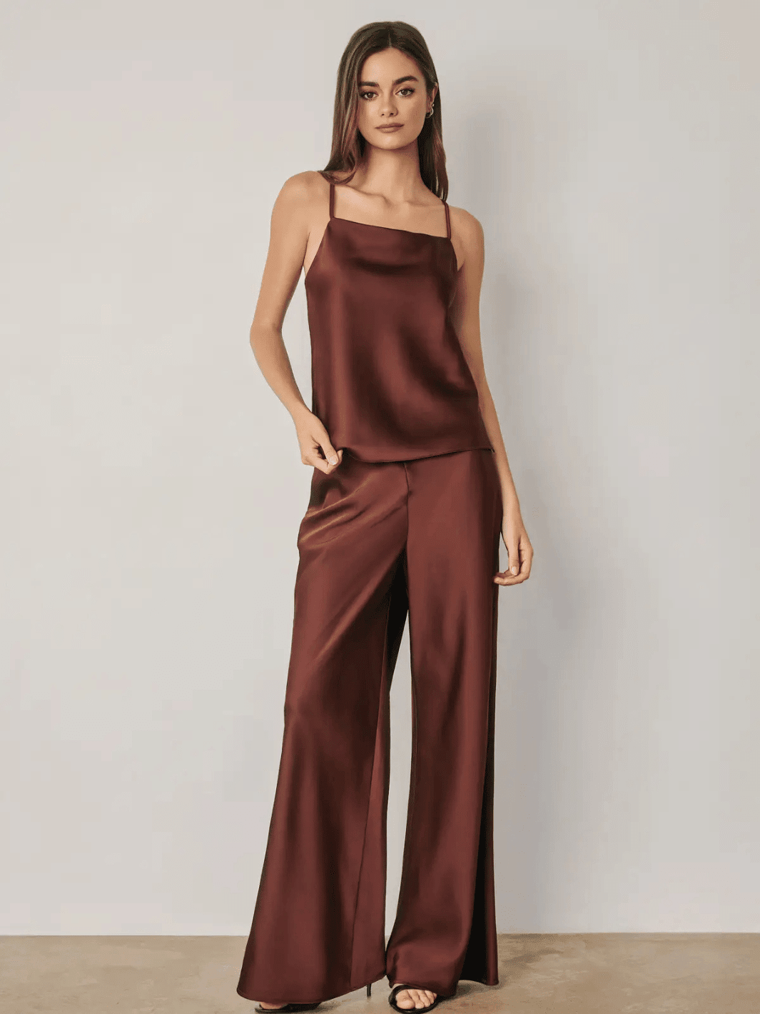 High-rise burgundy satin straight-leg pants with relaxed fit and bias-cut design, styled in a full-look with matching slip top for an elevated evening silhouette.