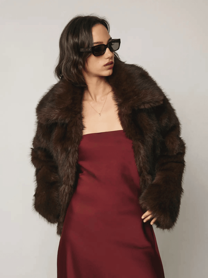 The Mocha Cloud Faux Fur Jacket in Chocolate by Jayden P Boutique, styled over a burgundy strapless dress with black sunglasses.