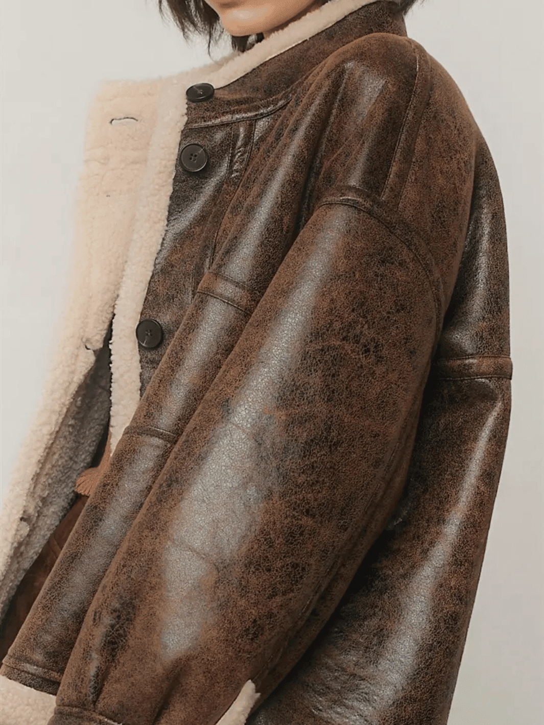 Close-up of The Renegade Shearling Moto Jacket from Jayden P Boutique, showing distressed brown faux leather, sherpa trim and buttons.