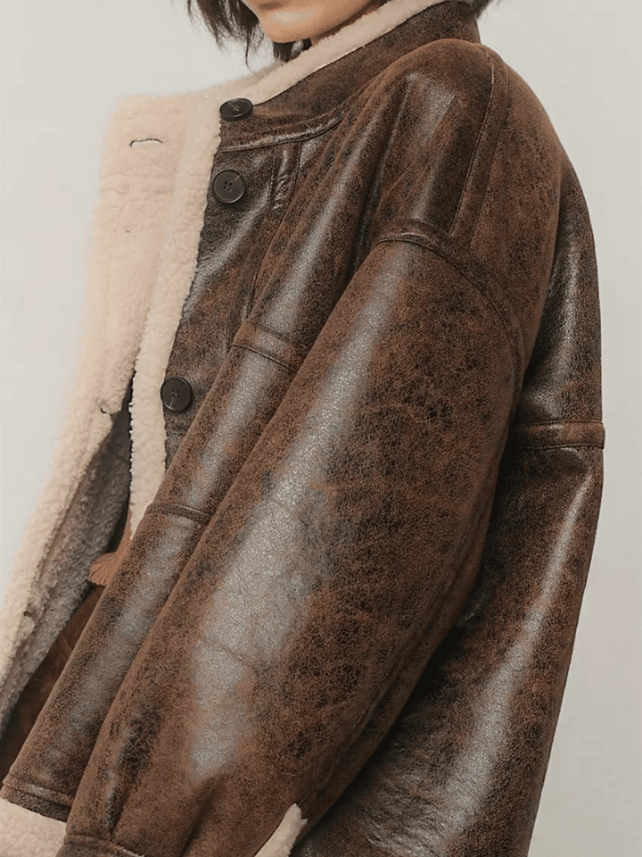 Close-up of The Renegade Shearling Moto Jacket from Jayden P Boutique, showing distressed brown faux leather, sherpa trim and buttons.