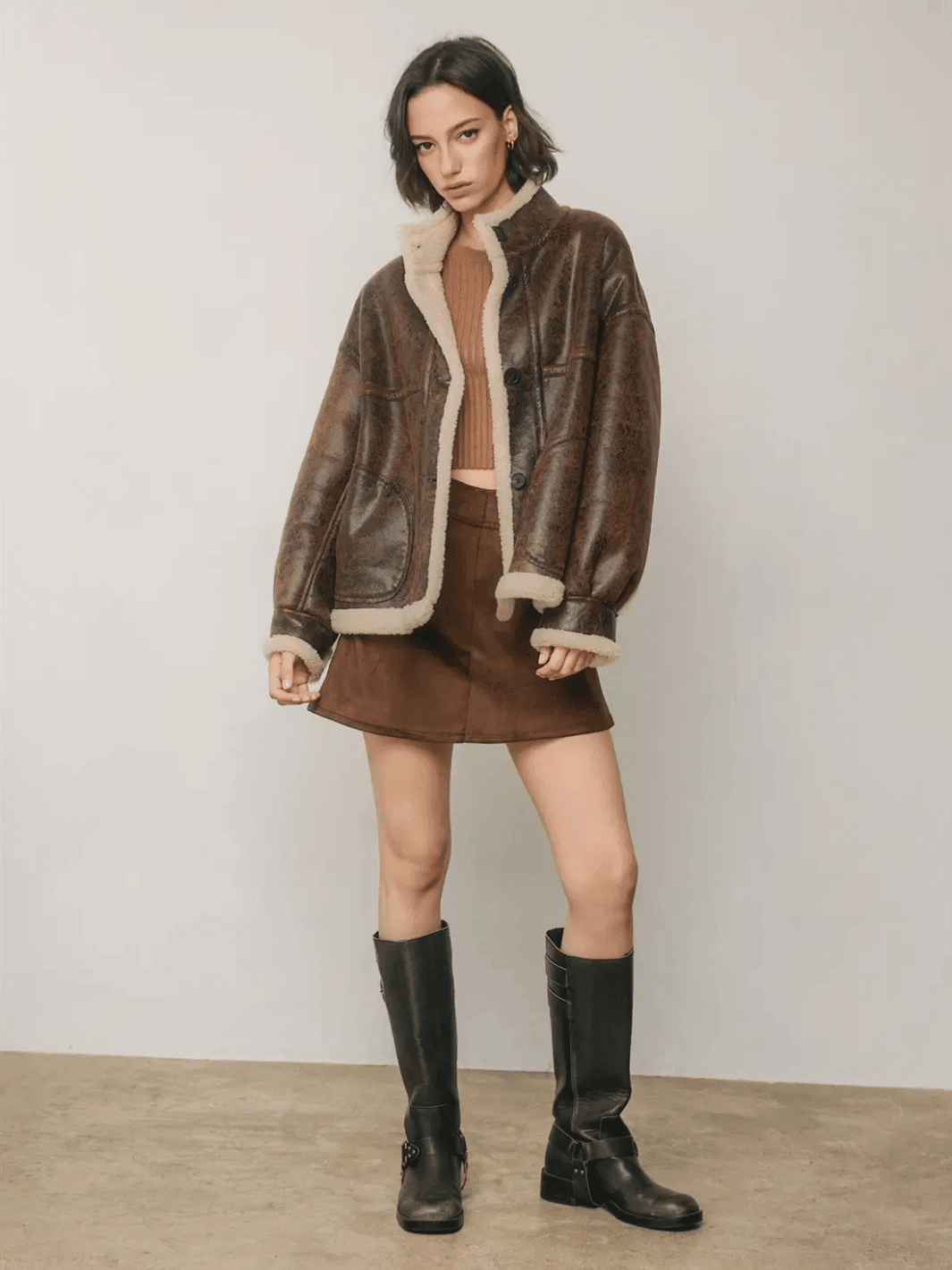 Full-length front view of The Renegade Shearling Moto Jacket in distressed brown, styled with mini skirt and boots by Jayden P Boutique.
