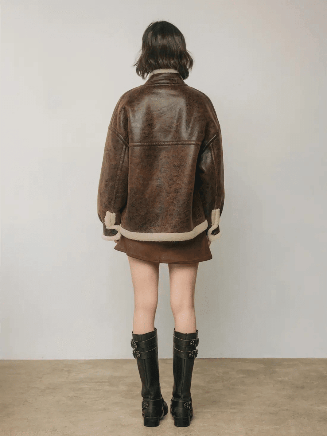Full-length back view of The Renegade Shearling Moto Jacket in distressed brown, styled with mini skirt and boots by Jayden P Boutique.