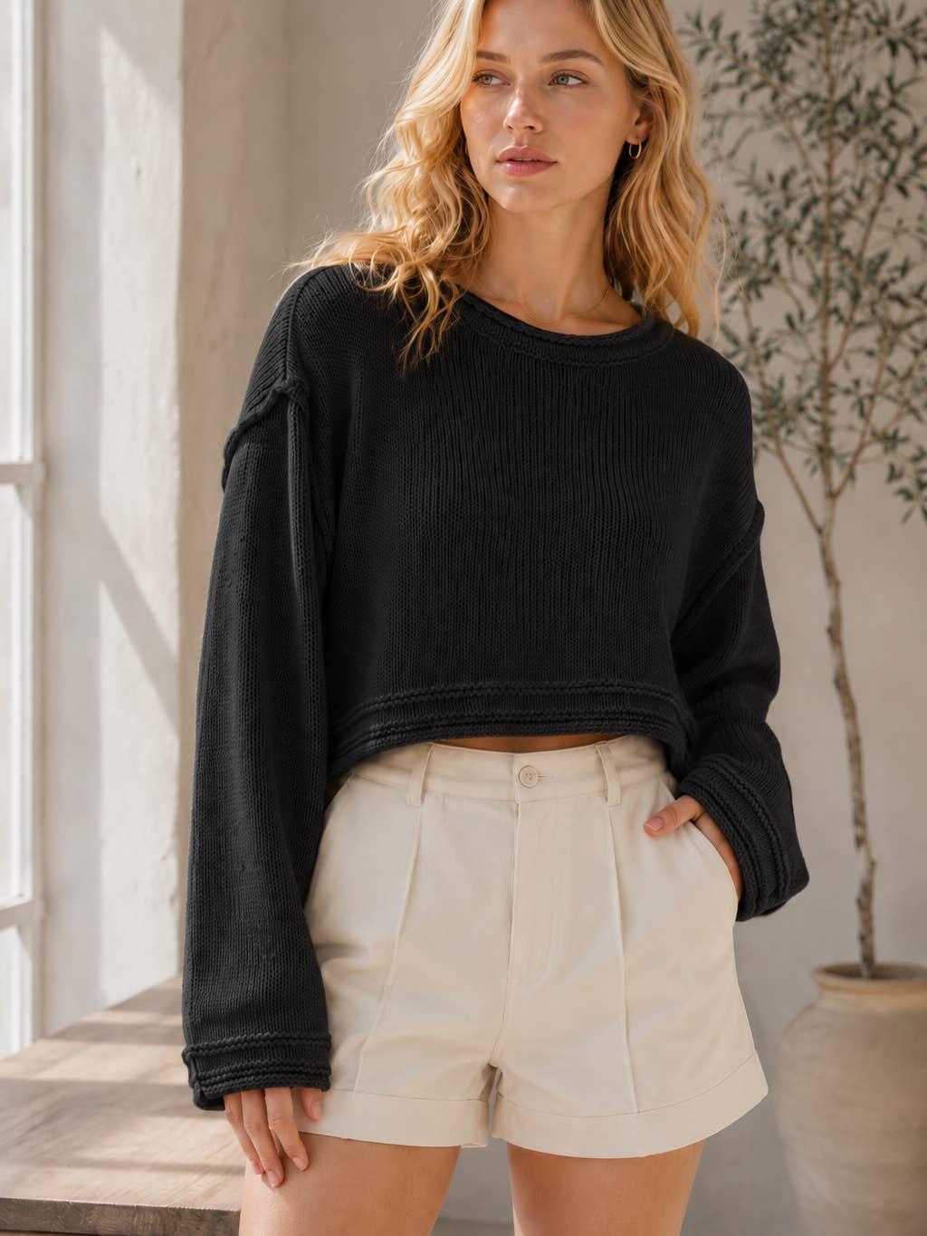The Wren Relaxed Cropped Knit Sweater in Black — loose crew neck knit with long sleeves, styled with cream shorts | Jayden P Boutique